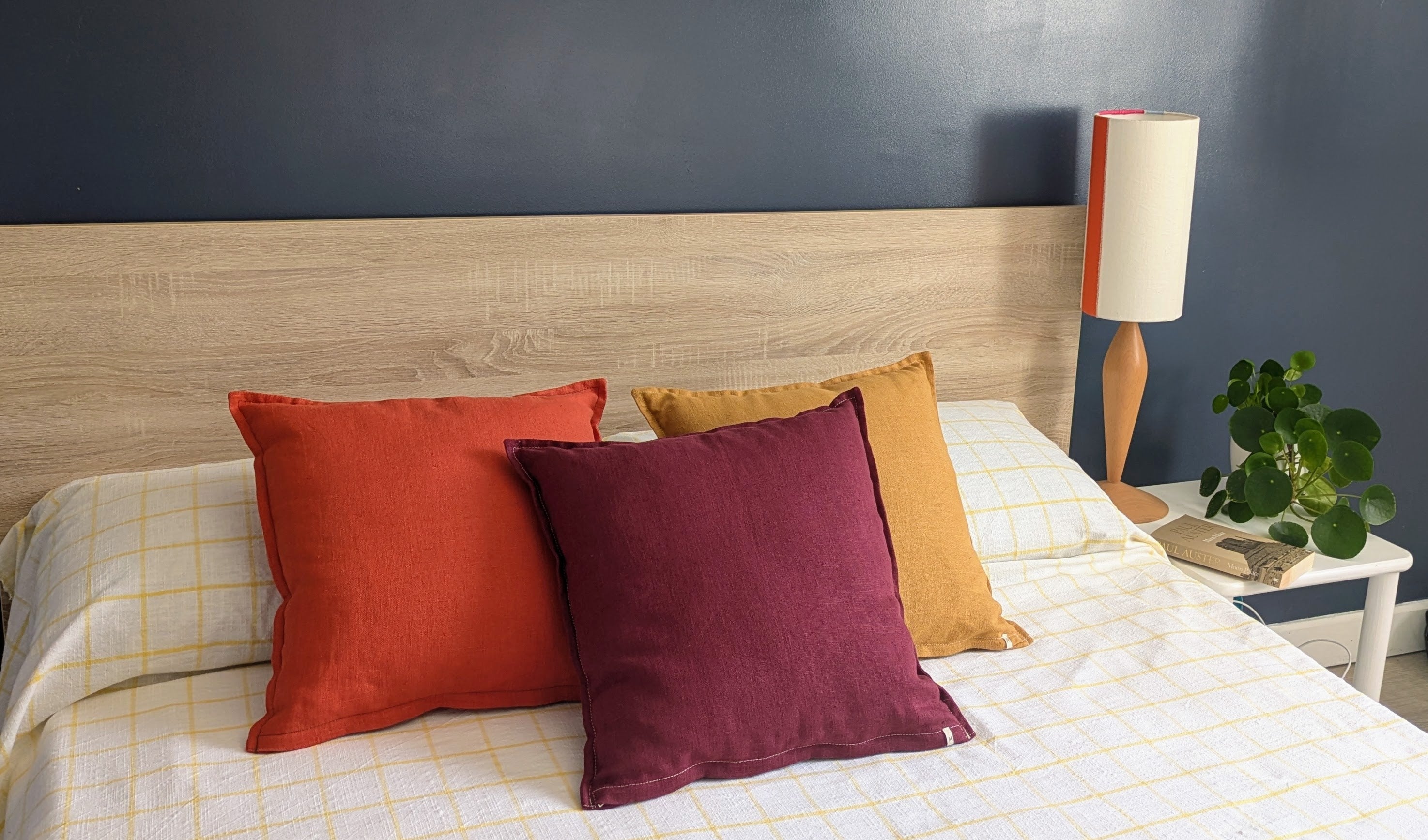 Housses de coussin en lin français terracotta, bordeaux et ocre sur lit — collection Mokiko