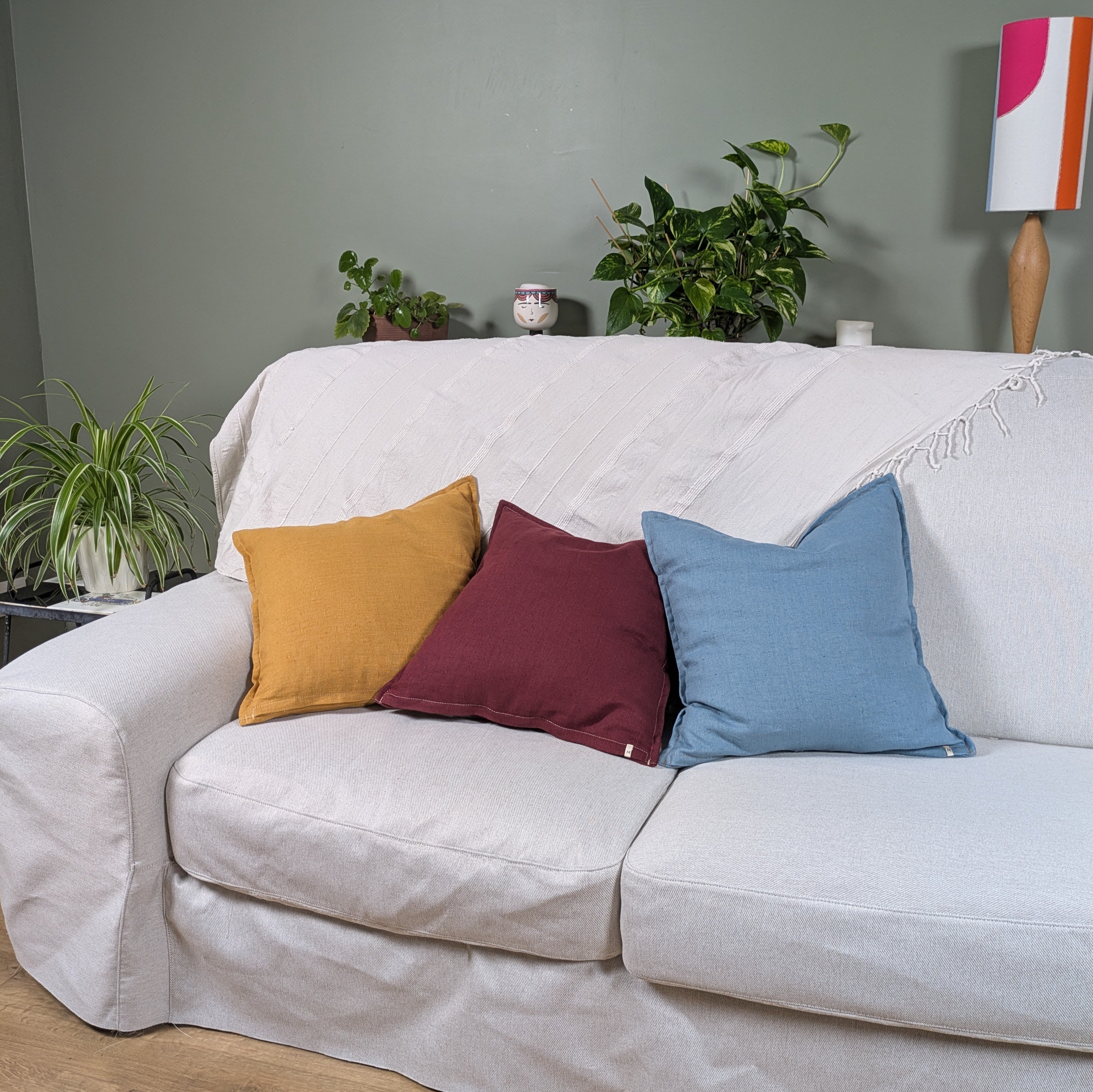 Housses de coussin en lin moutarde, bleu et bordeaux sur canapé blanc - collection Mokiko