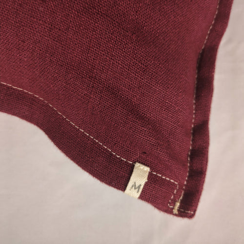 Détail texture lin français bordeaux, surpiqûre écrue — housse de coussin Mokiko