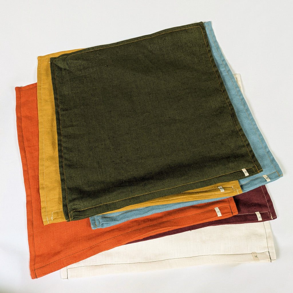 Housses de coussin en lin français empilées, coloris moutarde, bordeaux, terracotta, kaki, écru et bleu — Mokiko