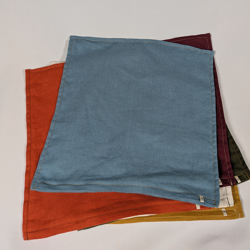 Housses de coussin en lin français empilées, coloris moutarde, bordeaux, terracotta, kaki, écru et bleu — Mokiko